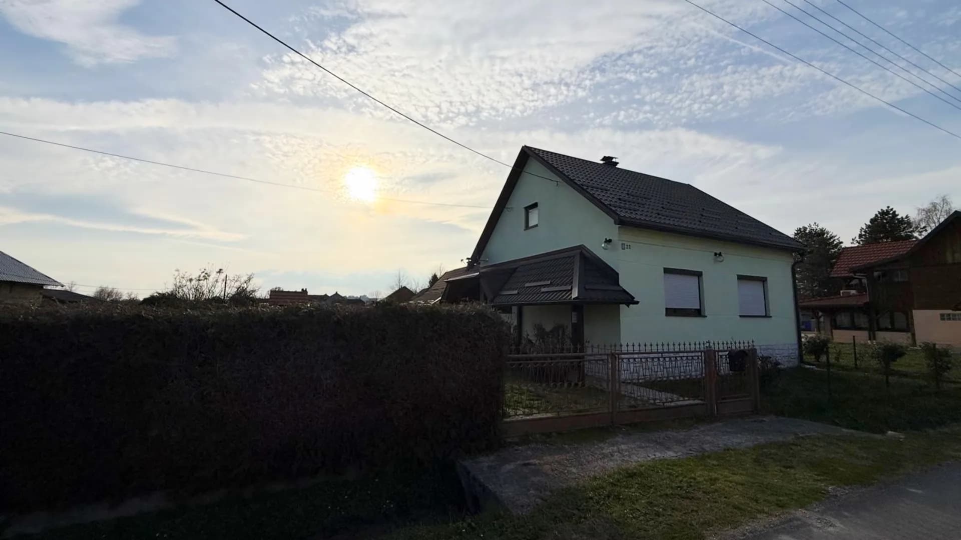 Obiteljska kuća iza živice u suton, obiteljska kuća u Draganiću